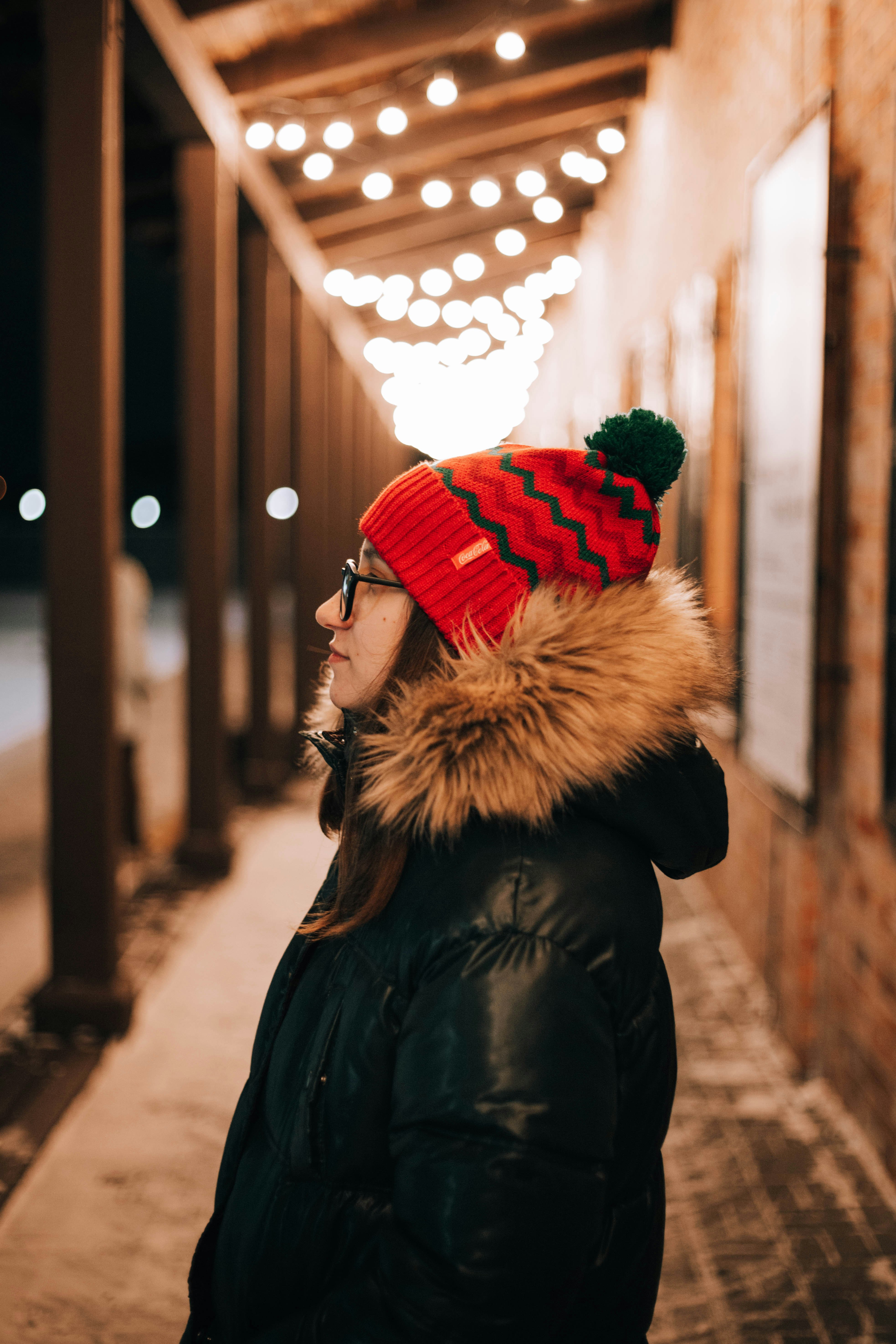 woman in black and brown parka jacket wearing red and white knit cap